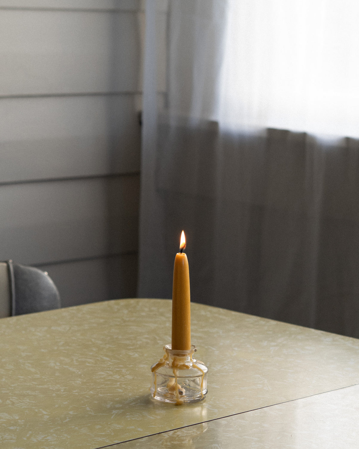 Bishops Remedy Hand-dipped Daily Taper Candle on a retro dining table.