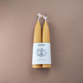 Two hand made beeswax candles with a white label on a brown background